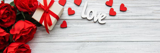 Cup of tart and ruby red hibiscus tea on valentines background with red roses, a gift box, and 'love' cutout | tea + munchies