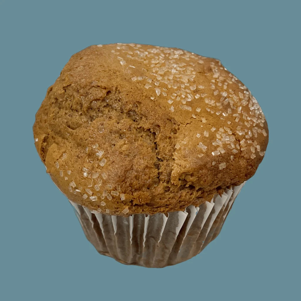 A tempting Gingerbread Muffin, sprinkled with crunchy sugar crystals. Has a golden-brown exterior and moist, spiced interior. A delightful winter treat that captures the essence of holiday warmth and indulgence. On a teal background. | tea + munchies