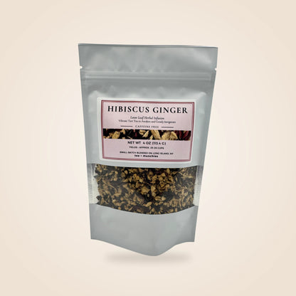 A white stand-up pouch of Hibiscus Ginger herbal supplement with a clear window showing the dried flower and ginger blend inside, set against a solid light beige background.