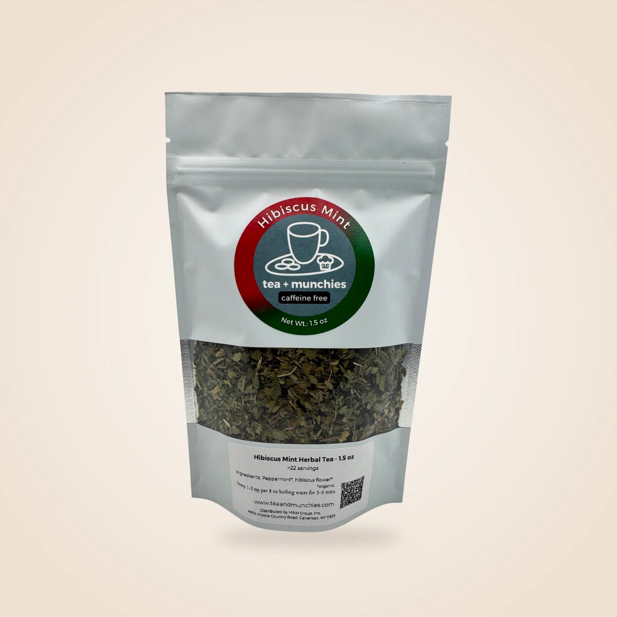 A white stand-up pouch of Hibiscus Mint herbal tea by tea + munchies, featuring a circular red and green logo and a clear window showing the dried green tea inside, set against a solid light beige background.