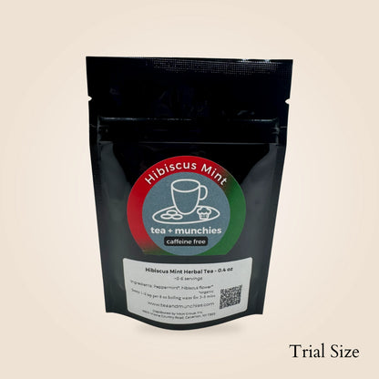 A black stand-up pouch of Hibiscus Mint tea + munchies, featuring a circular red, green, and blue label with a teacup icon, on a light beige background. The text 'Trial Size' is printed in the bottom right corner.