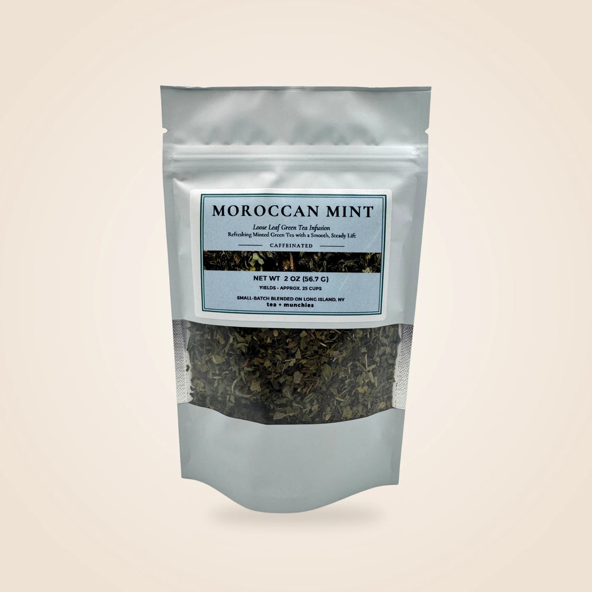 A 2 oz resealable stand-up pouch of Moroccan Mint loose-leaf tea on a light beige background. The white pouch features a clear window showing the dark green tea leaves inside and a white label with blue text.