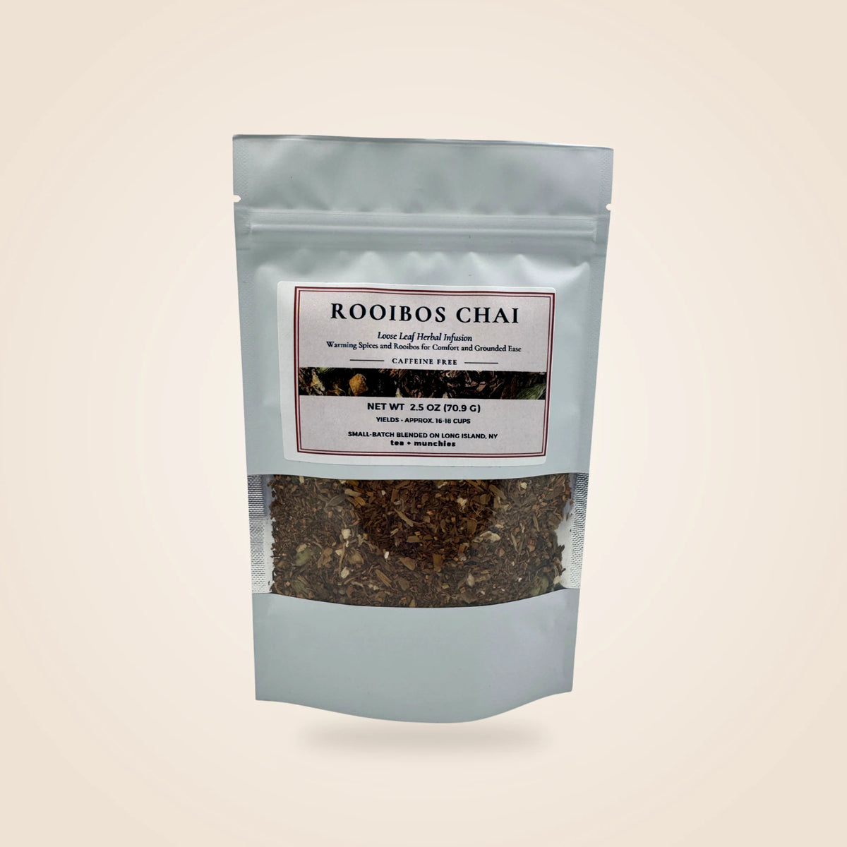 A white stand-up pouch of Rooibos Chai loose leaf herbal infusion with a clear window showing the dark brown tea blend inside, set against a solid light beige background.