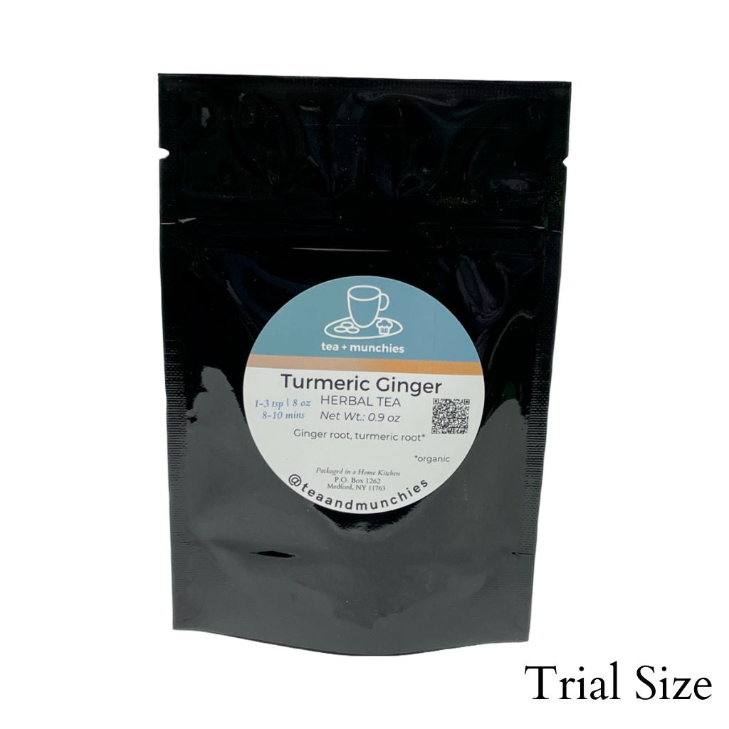Resealable black glossy stand-up package of trial size loose leaf turmeric ginger herbal tea on white background. 'Trial size' written in lower right hand corner | tea + munchies